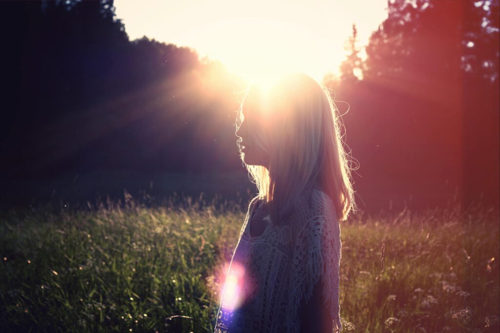 Vrouw in een veld bij zonsondergang, in gedachten verzonken